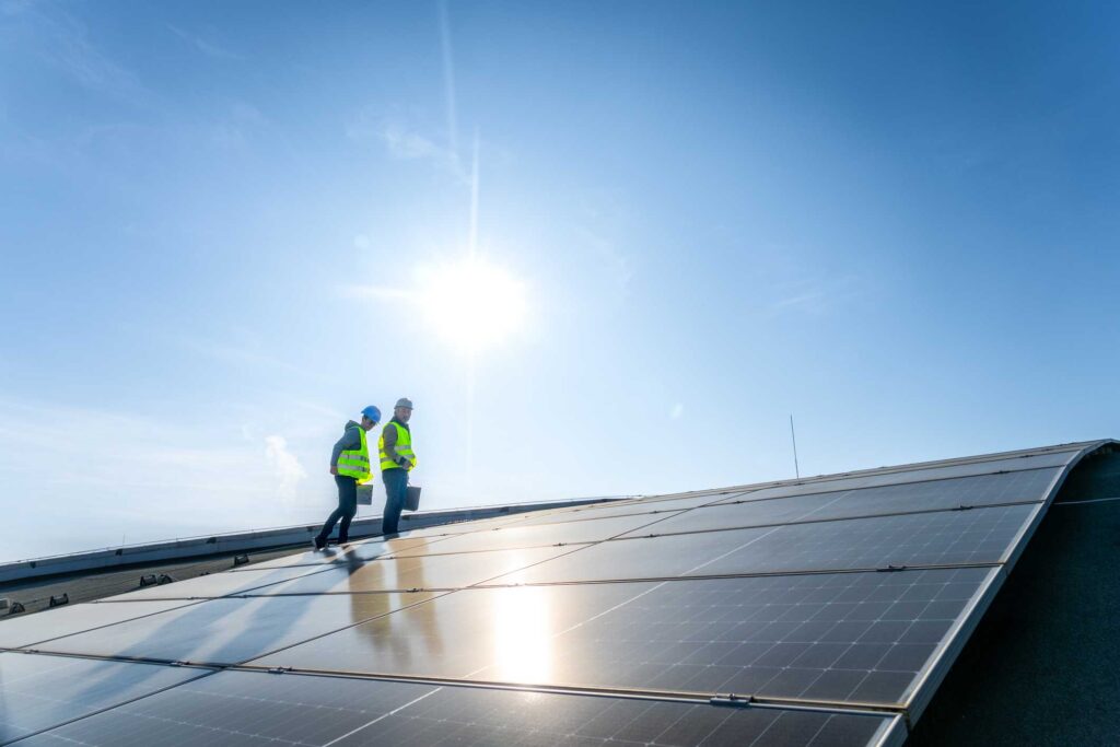 Two technicians inspecting solar panels under, monitoring system health