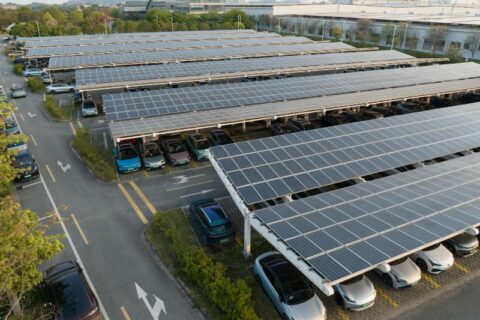 Solar carport covering parking lot with vehicles in New England & Beyond