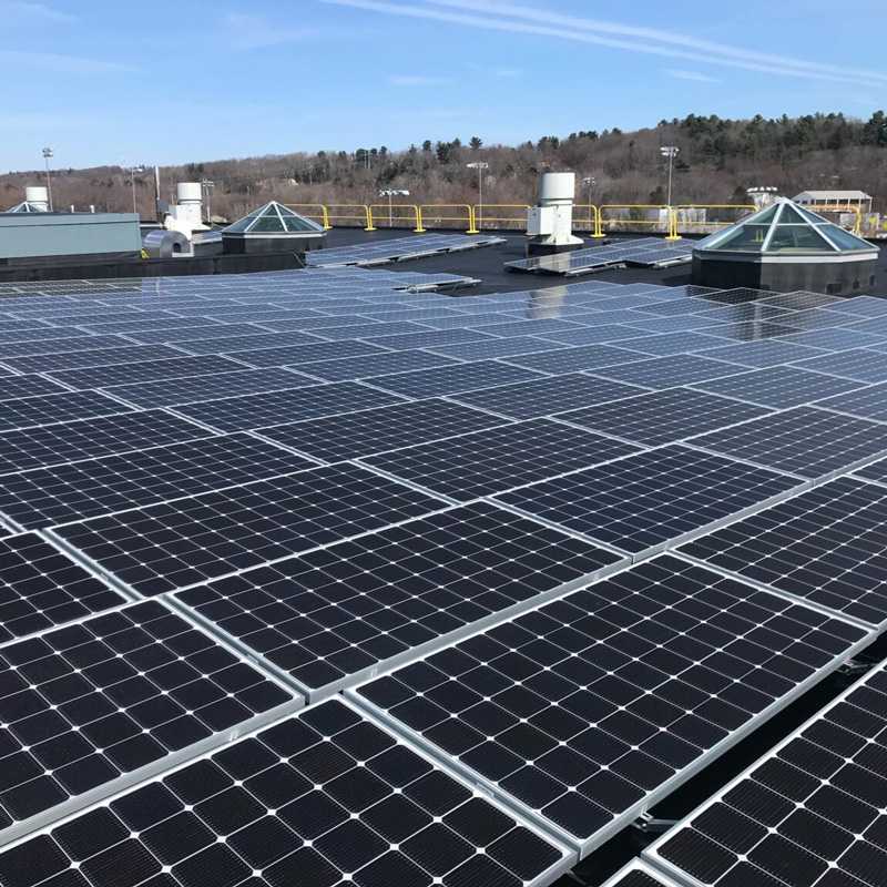 Solar Panels Installed on the Rooftop of a High School Building Surrounded by Woodland in Auburn, MA